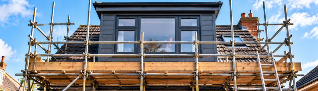 Loft Conversions with a dormer roof extension, skylight and scaffolded home, showing plans and safety equipment during construction work on a residential property and roof works in progress.